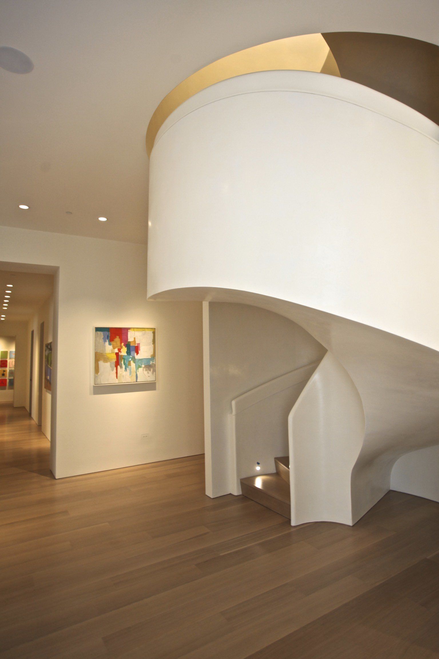 A white spiral staircase in a hallway with a painting on the wall