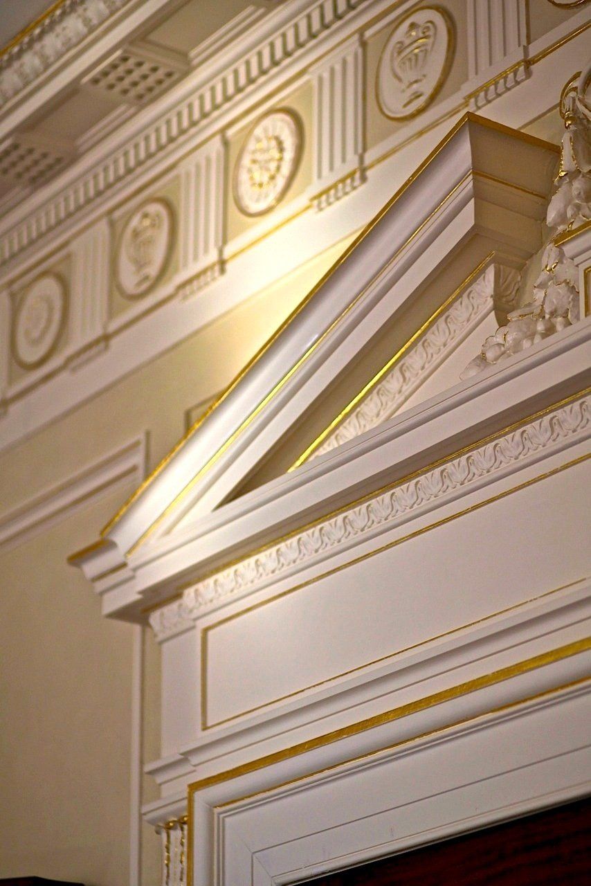 A white building with a gold trim and a red curtain