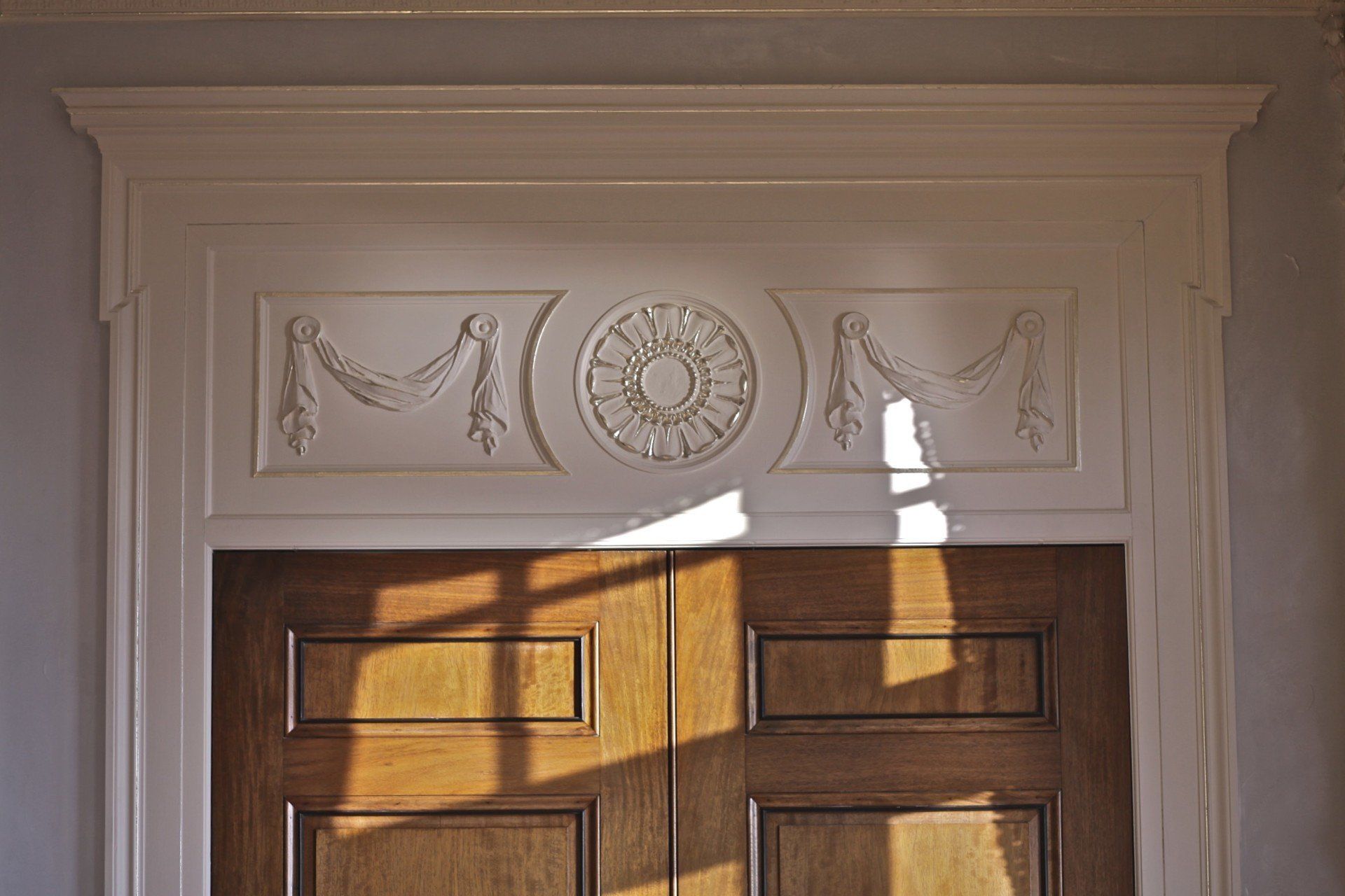 A wooden door with a white trim and a shadow on it.