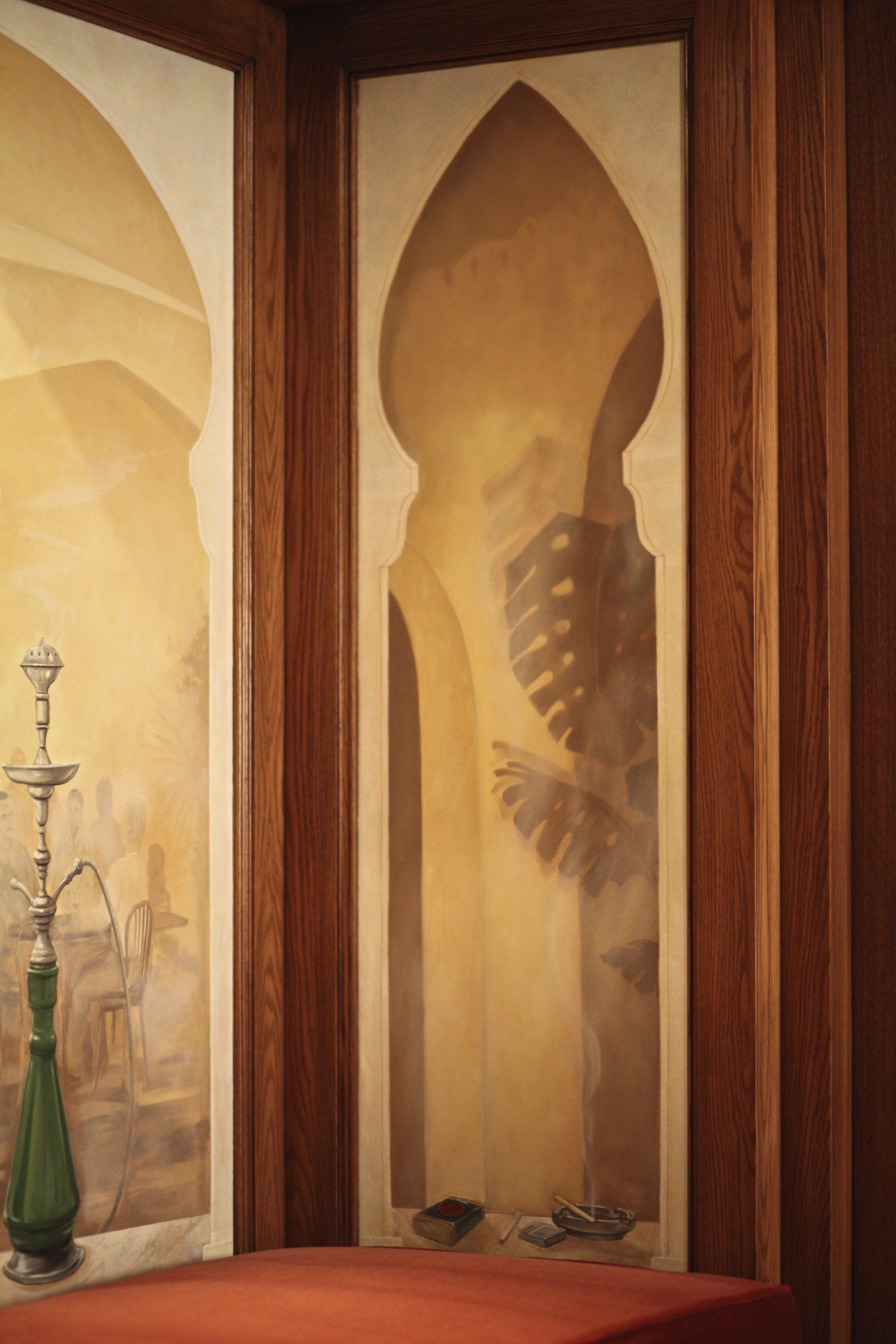 A hookah is sitting in front of a painting on a wall.