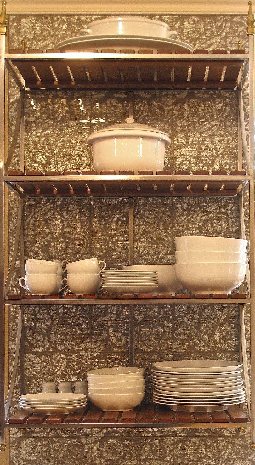 A shelf with plates , bowls , cups and a pot on it