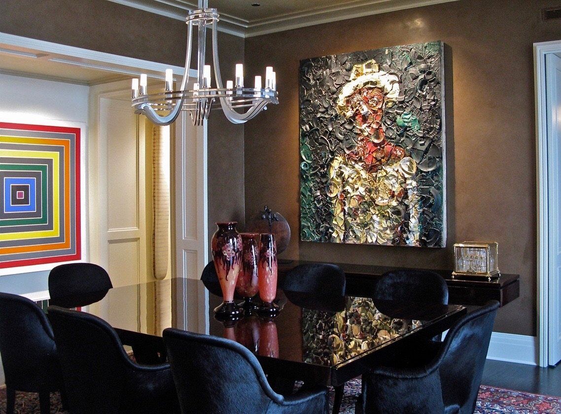 A dining room with a table and chairs and a painting on the wall