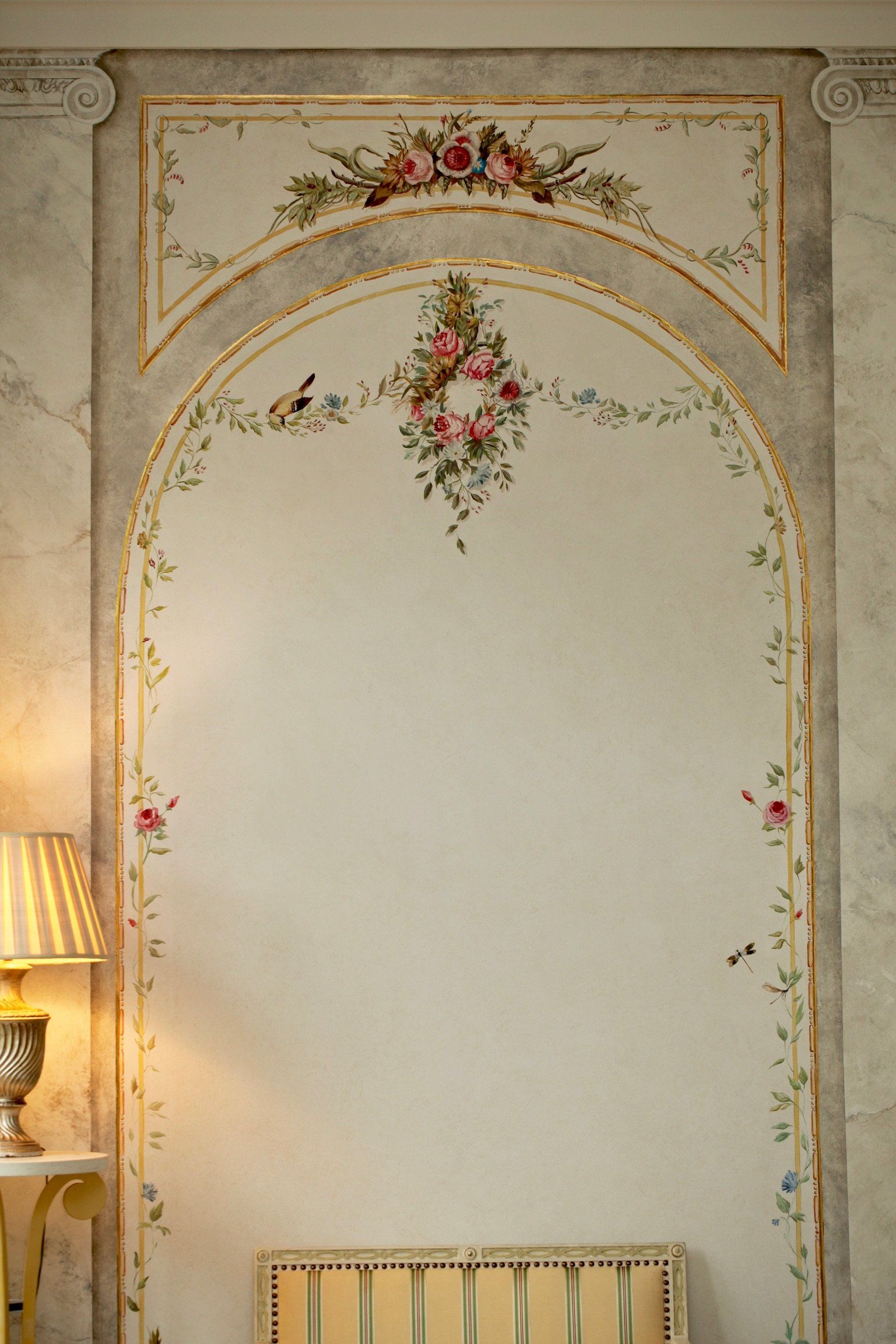 A wall with a painting of flowers and birds on it