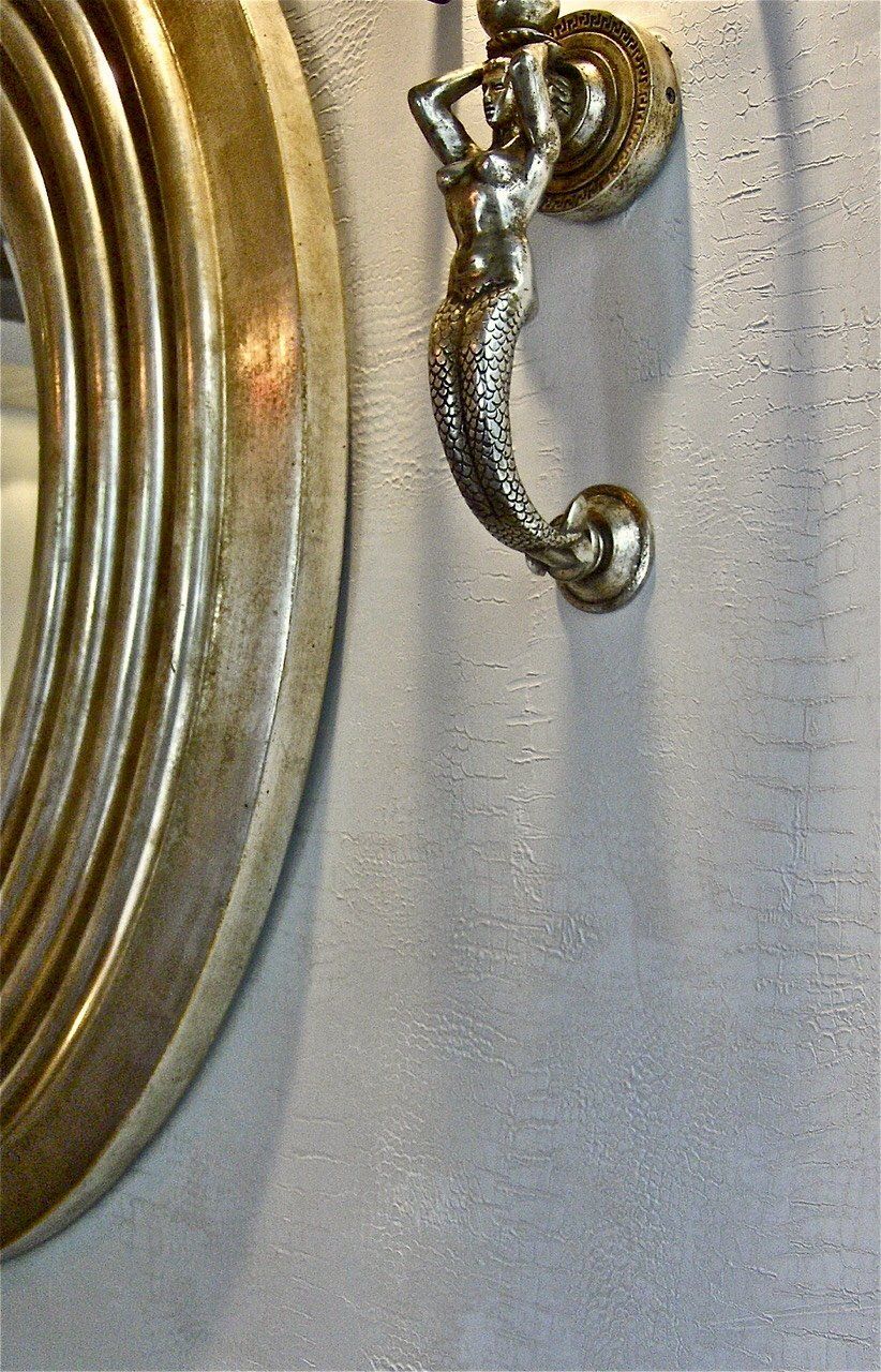 A mirror and a door knocker on a white wall