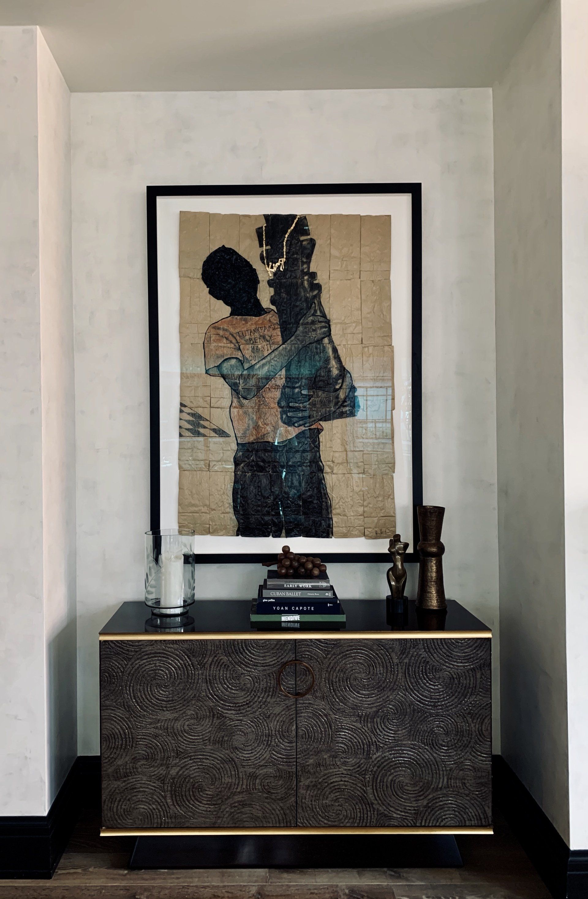 A painting of a man hugging another man is hanging on a wall above a table.