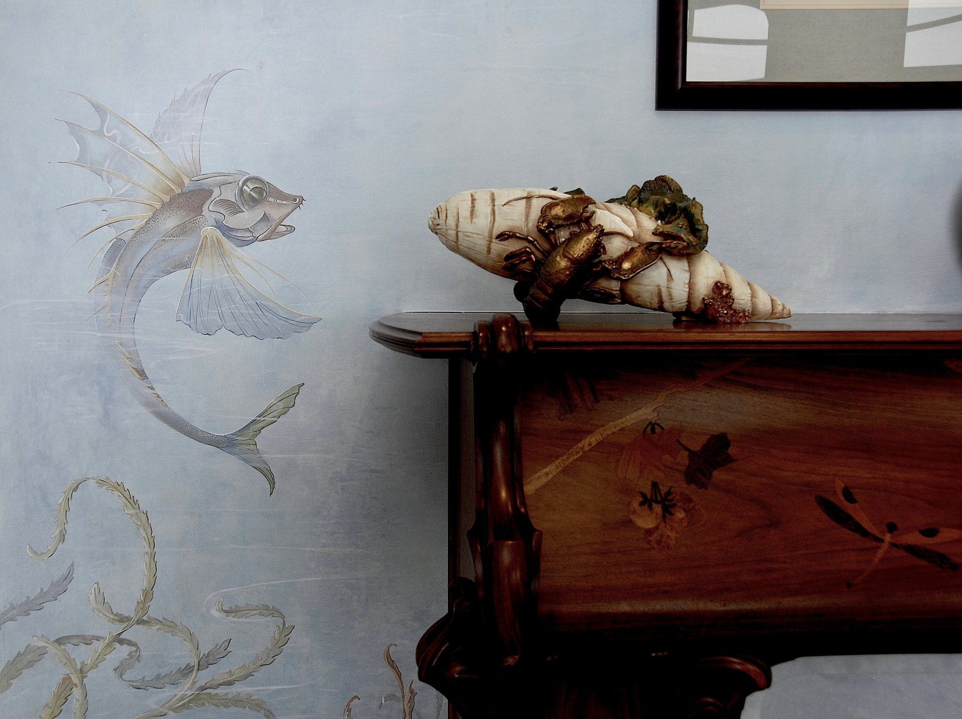 A wooden table with a painting of a fish on the wall behind it