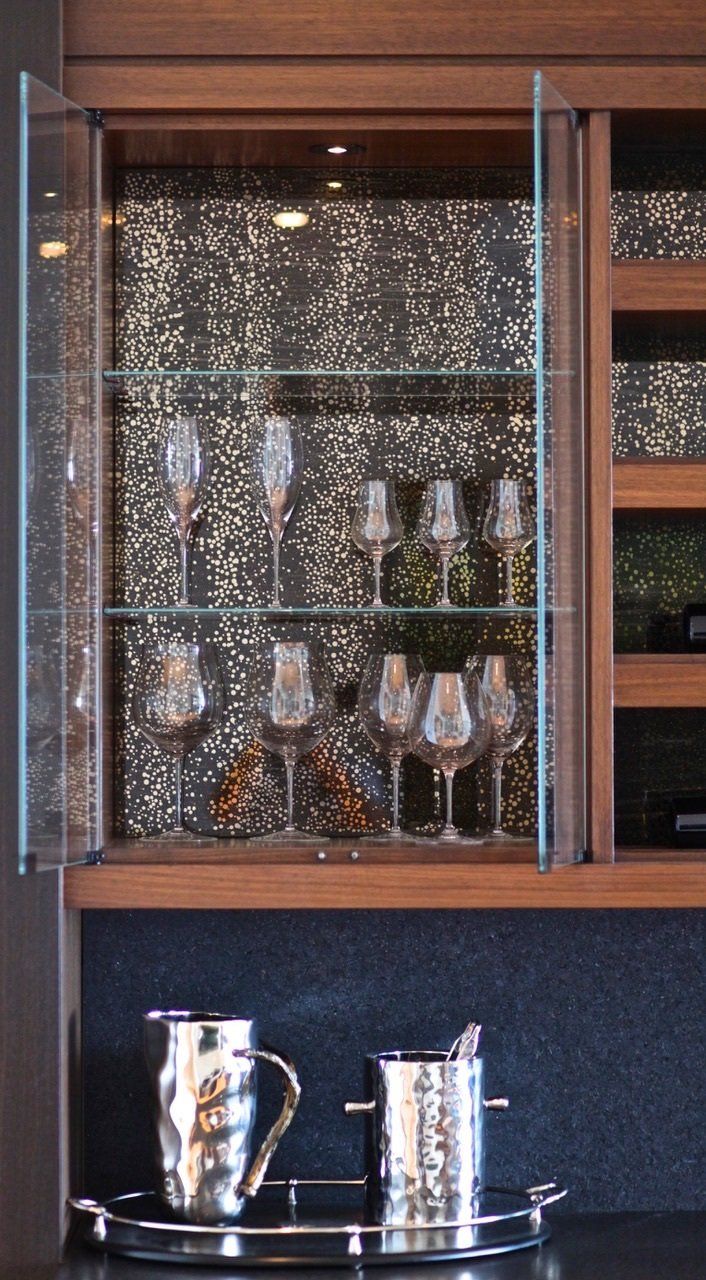A glass cabinet with a pitcher and ice bucket inside of it