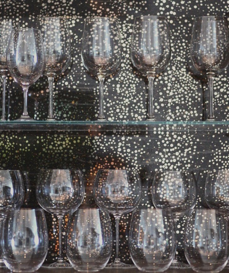 A row of wine glasses are lined up on a shelf