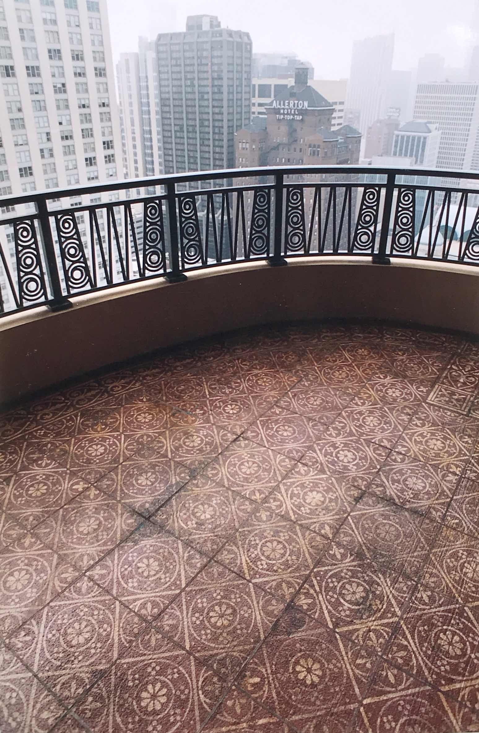 An empty balcony with a railing and a view of a city.
