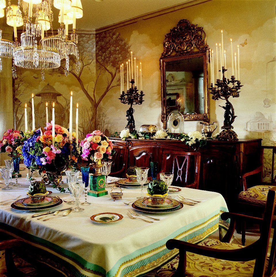 A dining room table with plates and candles on it