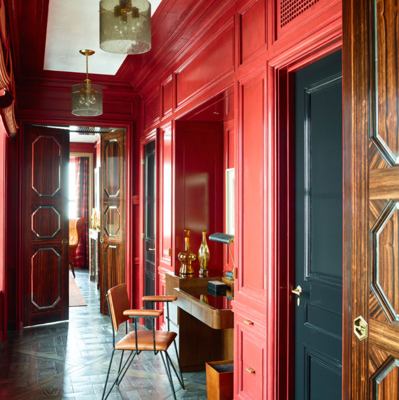 A hallway with red walls and black doors