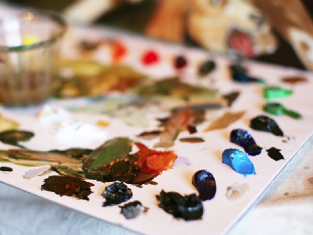 A close up of a painting palette with a dog in the background