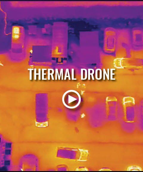 An aerial view of a thermal drone flying over a parking lot.