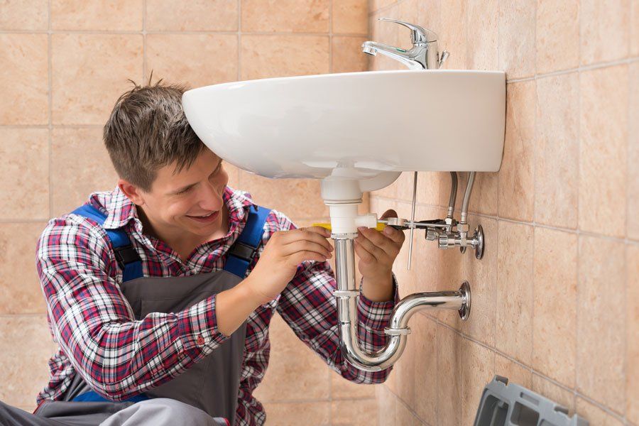 Smiling Plumber Repairing Sink — Allentown, PA — Fred J Moyer Plumbing Inc Smiling Plumber Repairing Sink — Allentown, PA — Fred J Moyer Plumbing Inc
