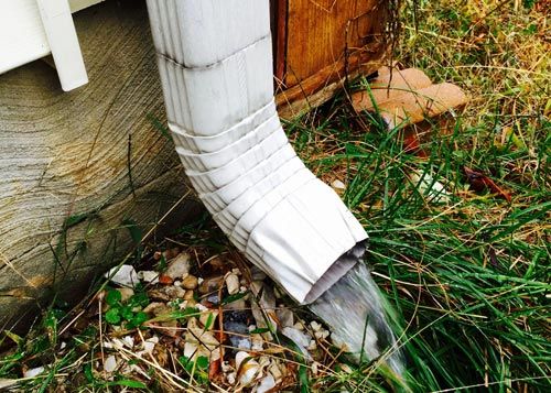 Rain gutter white gutter with rain coming out on grass