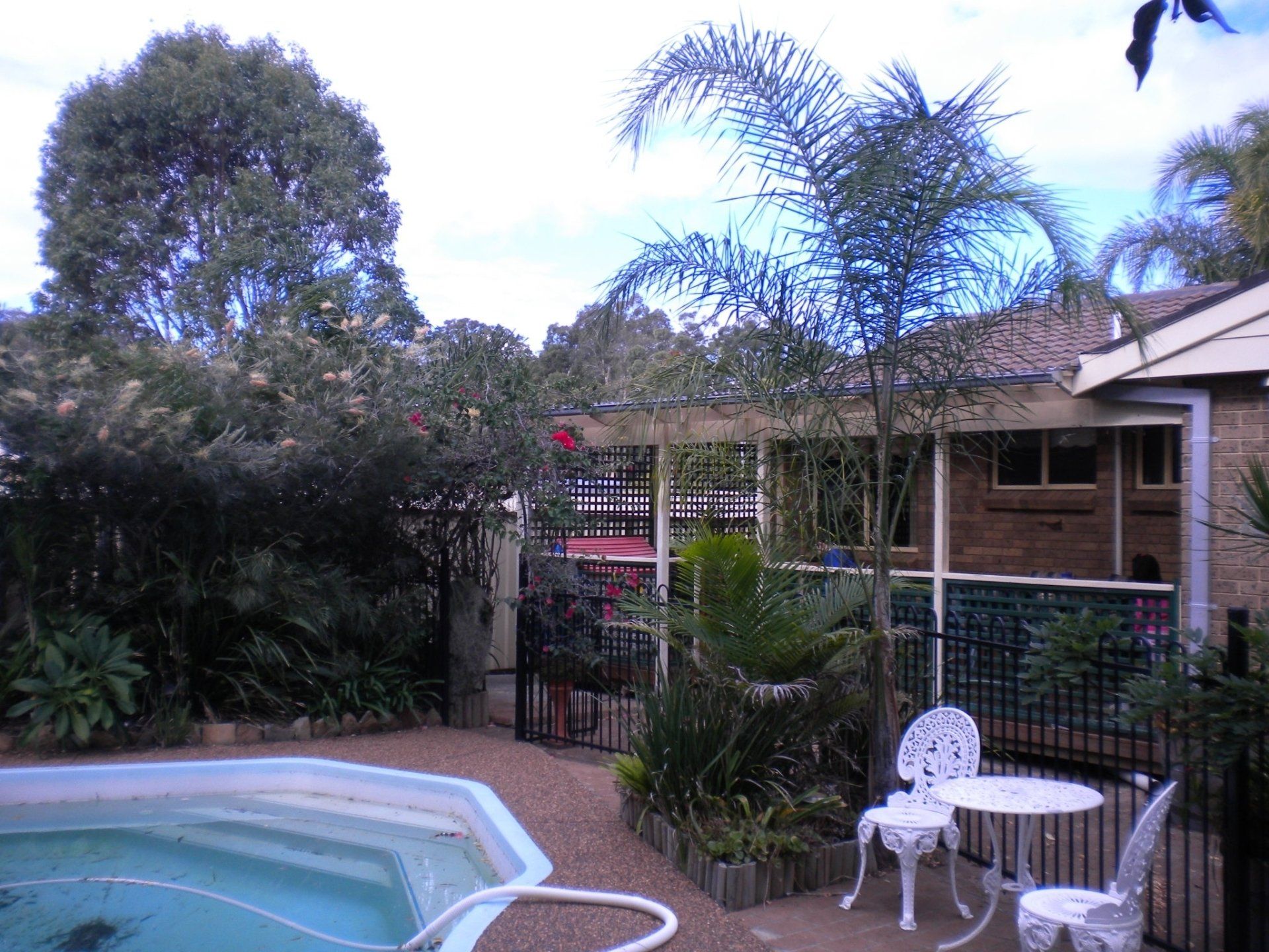 A swimming pool with a table and chairs in front of a house