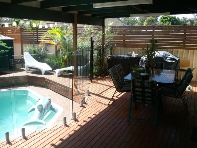 A deck with a table and chairs next to a pool