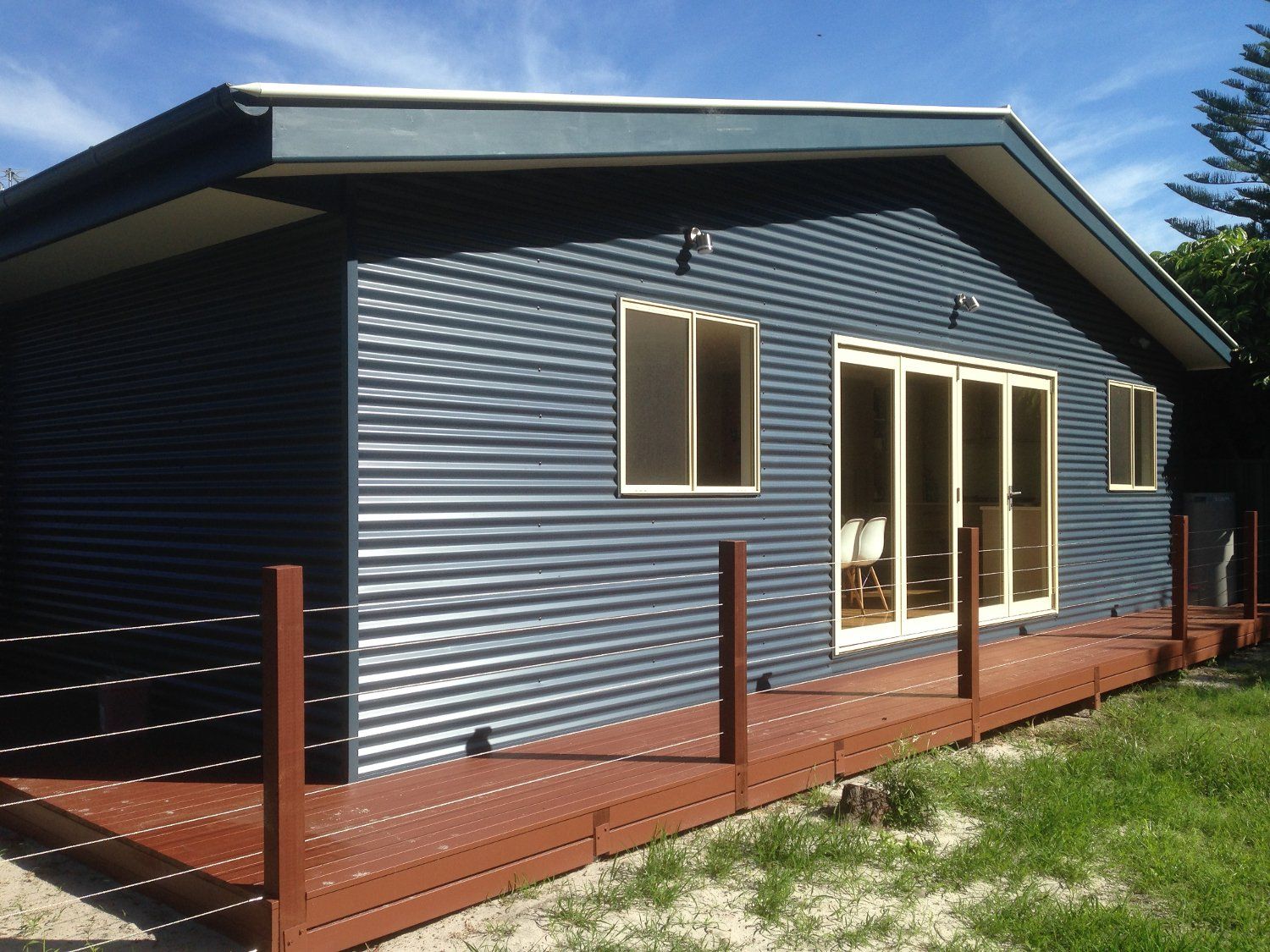 A blue house with a wooden deck in front of it
