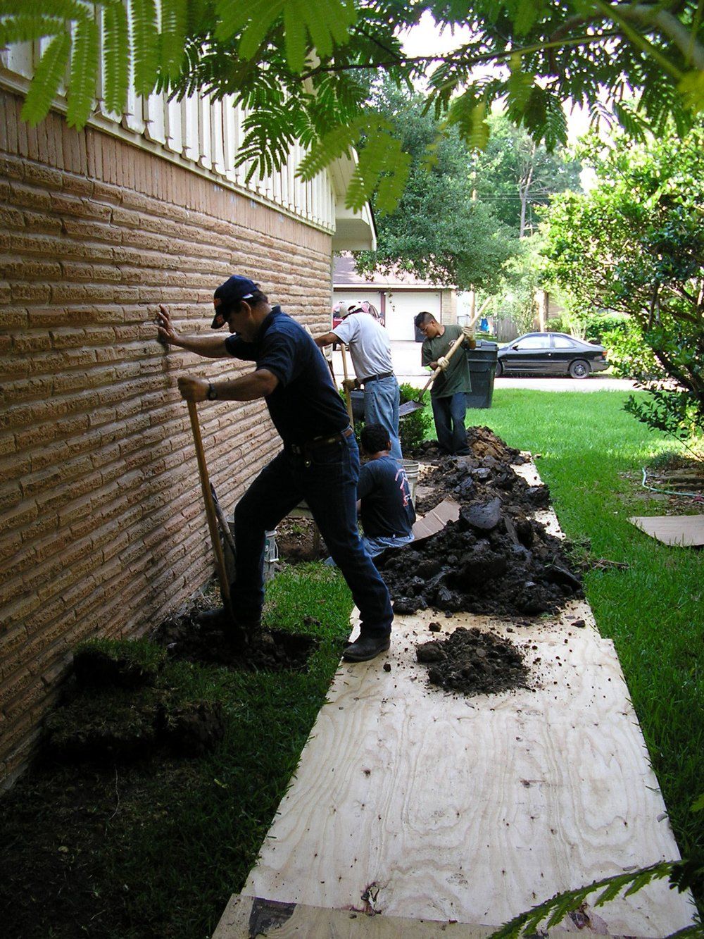 Workers Digging Near Wall — Bonilla Foundation Repair