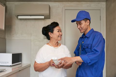 Residential HVAC — Male Technician Cleaning Air Conditioner in Phoenix, AZ Residential HVAC — Male Technician Cleaning Air Conditioner in Phoenix, AZ