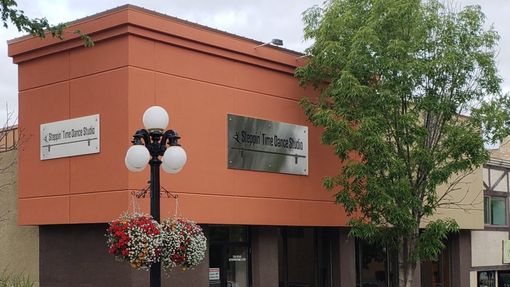 Orange building with storefront signs, a black streetlamp, and a tree in front.