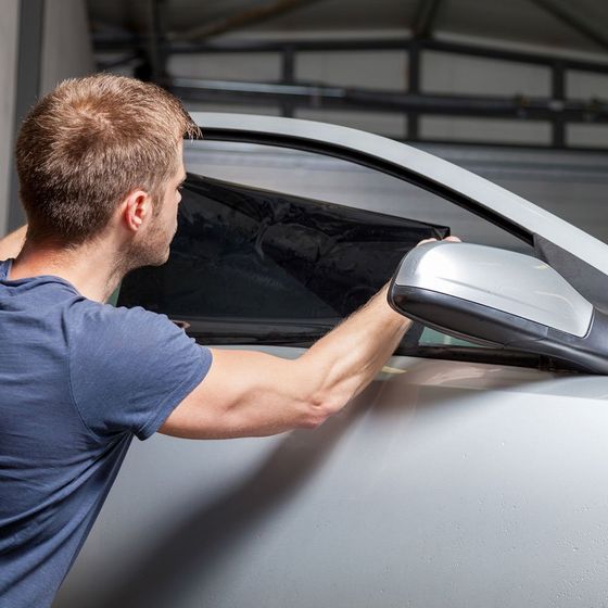 Car Window Tinting — Man Putting A Window Tint On A Silver Car in Glen Burnie, MD Car Window Tinting — Man Putting A Window Tint On A Silver Car in Glen Burnie, MD