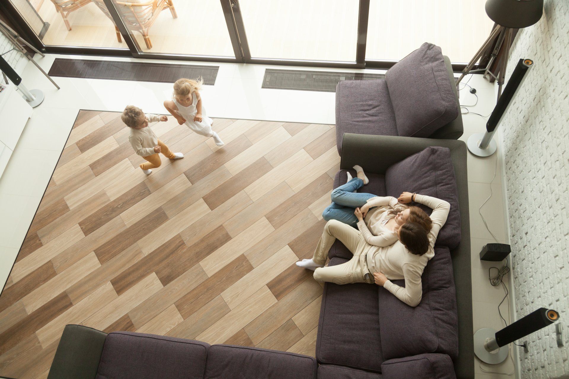 Two children playing near a sofa where a couple is cuddling in a modern living room.