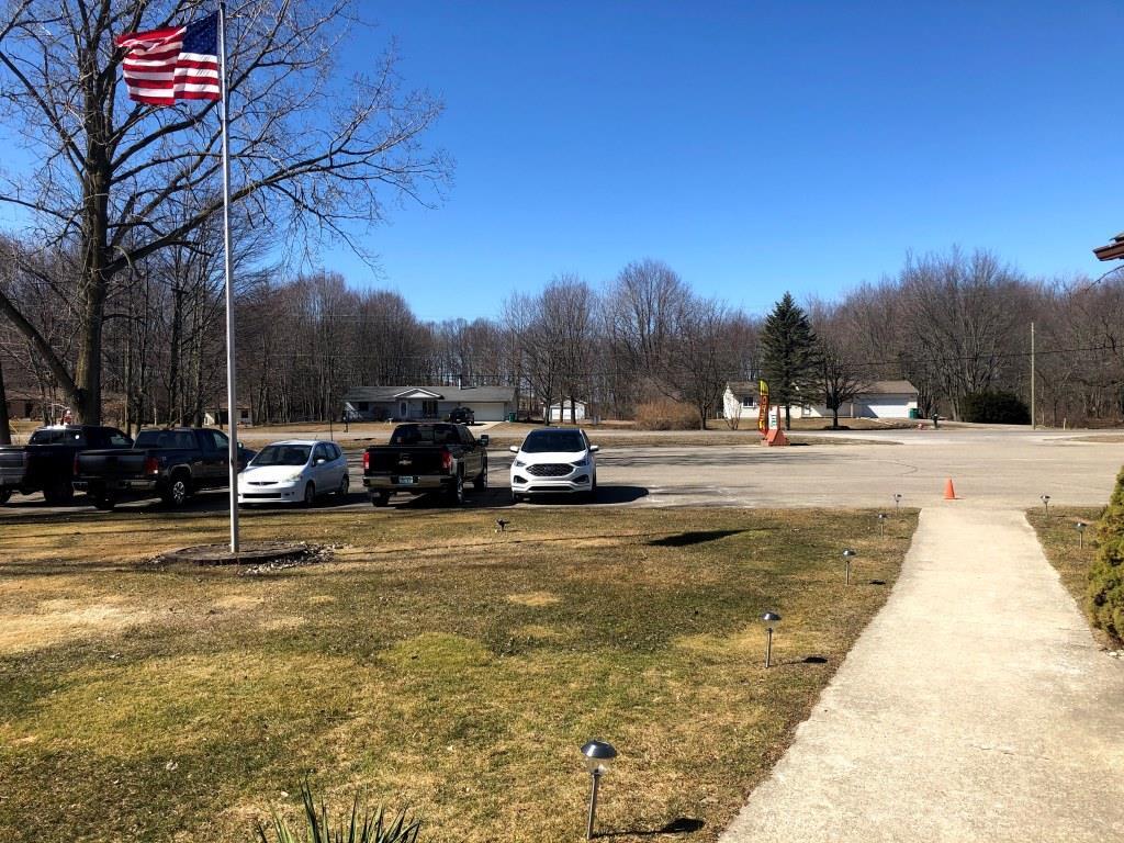 A row of cars are parked in a parking lot with an american flag in the background.