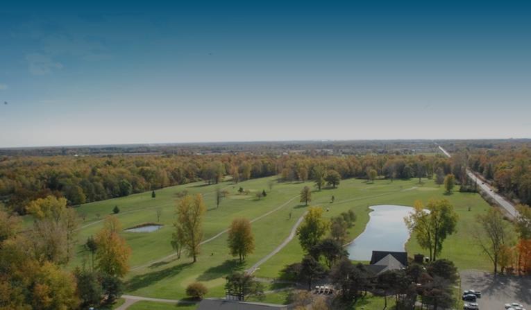 An aerial view of a golf course surrounded by trees and a lake.