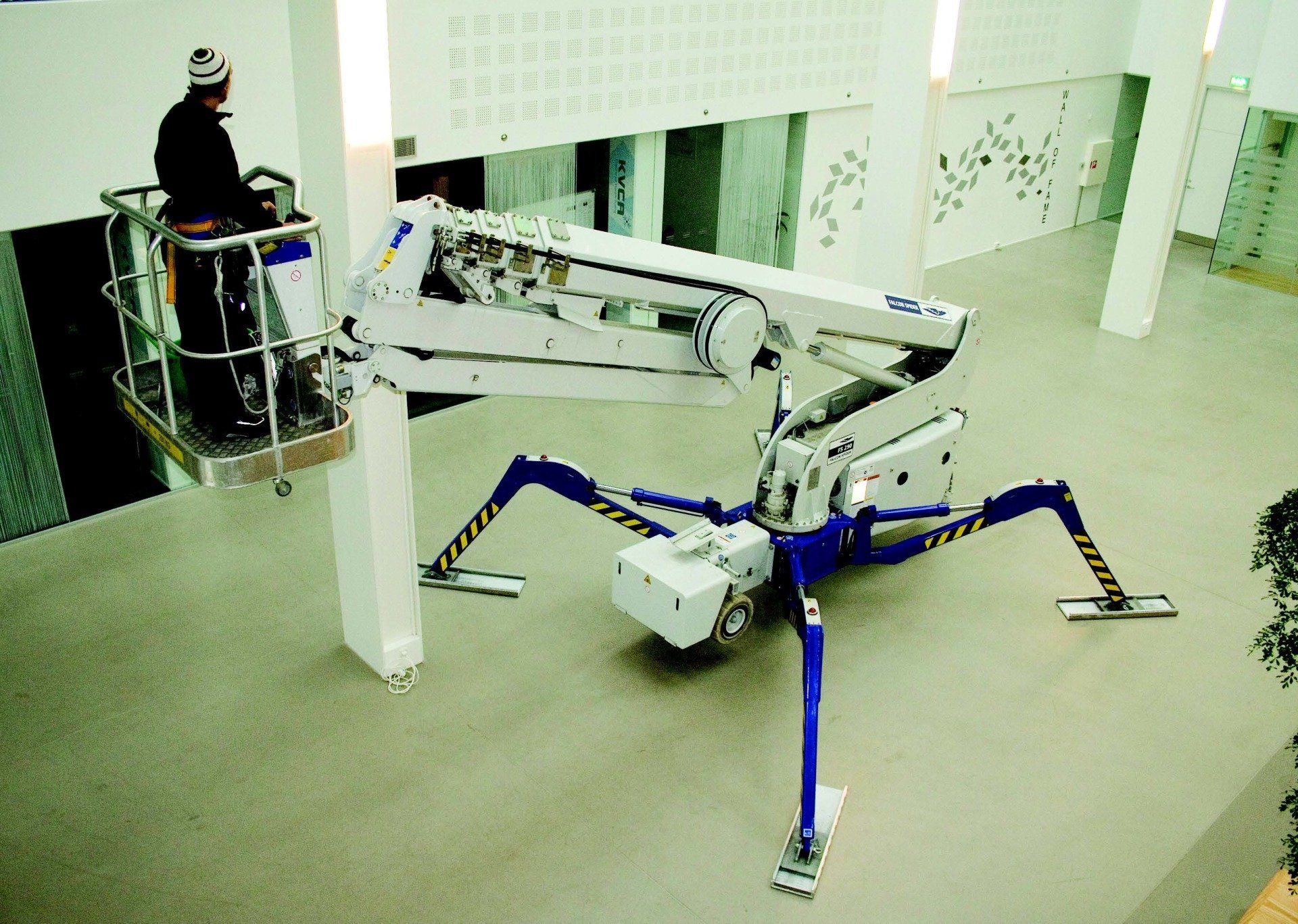 A man in a bucket is working on a machine that looks like a spider
