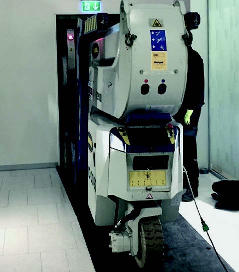 A man is standing next to a machine that has a warning sign on it