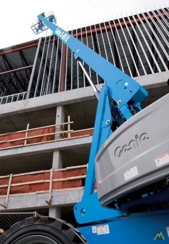A genie lift is sitting in front of a building under construction.