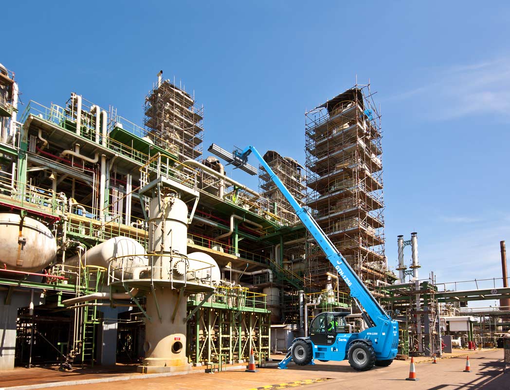 A crane is sitting in front of a large building in a factory.