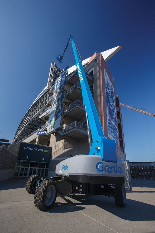 A genie lift is parked in front of a large building.