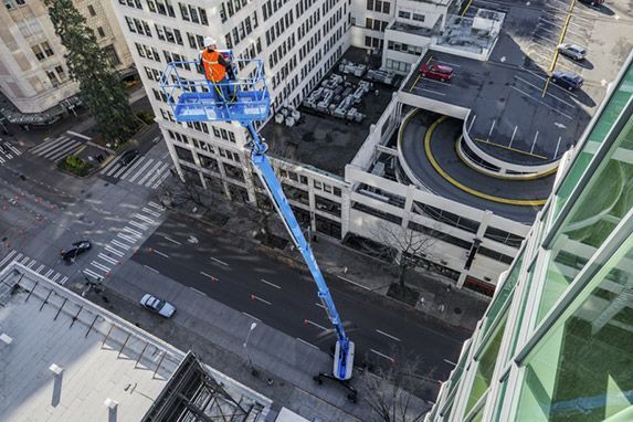 An aerial view of a man standing on a lift in front of a building.