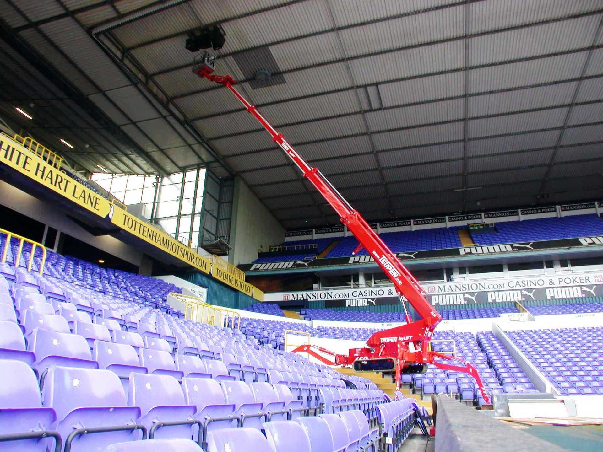 An empty stadium with purple seats and a red crane