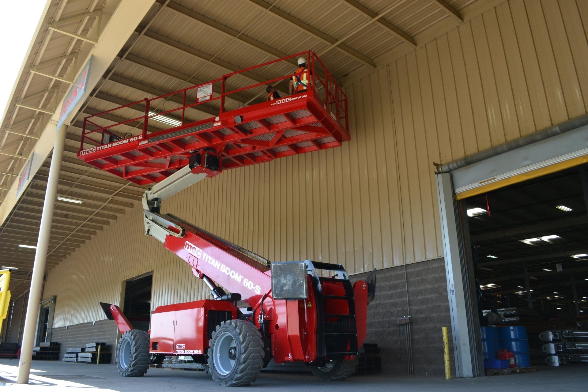 A red aerial lift is parked in front of a building.