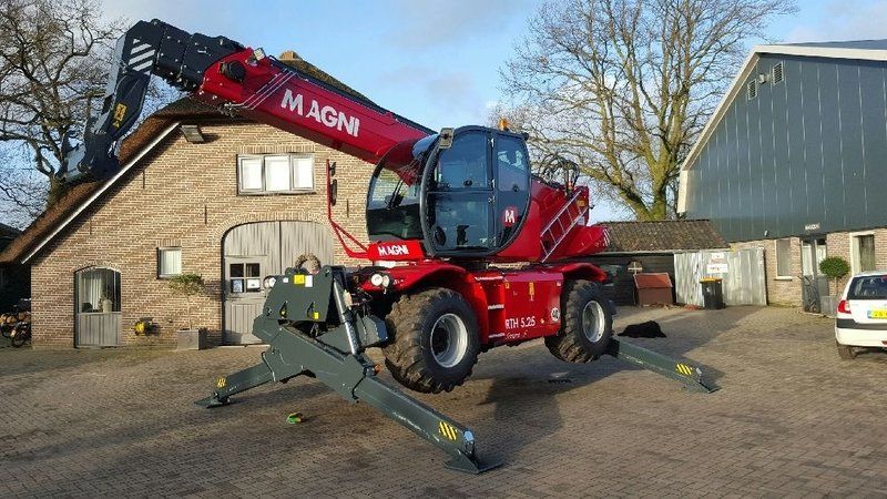 A red crane is parked in front of a brick building.