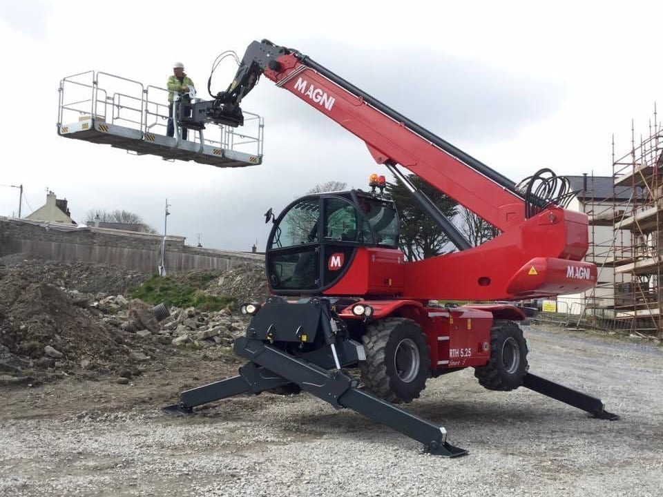 A man is standing on a platform on top of a red crane.