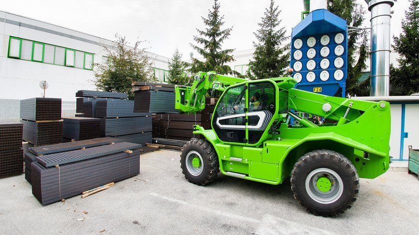 A green forklift is parked in front of a building.