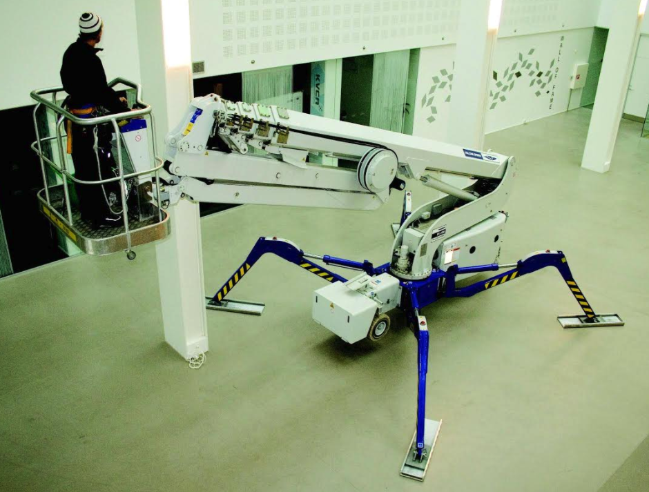 A man is working on a spider lift in a building.