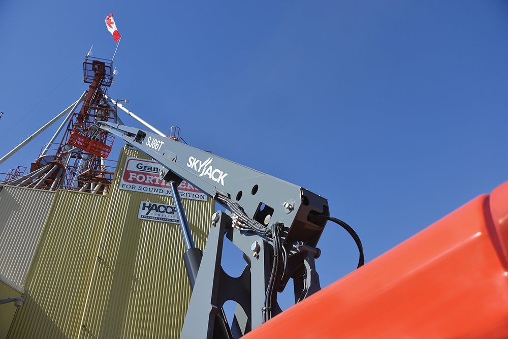 A skyjack crane is sitting in front of a building.