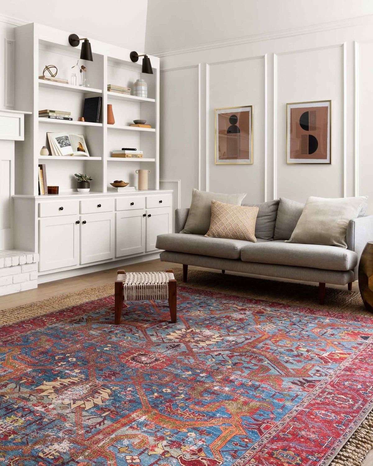 Bright living room with white shelves, gray sofa, and large colorful patterned rug