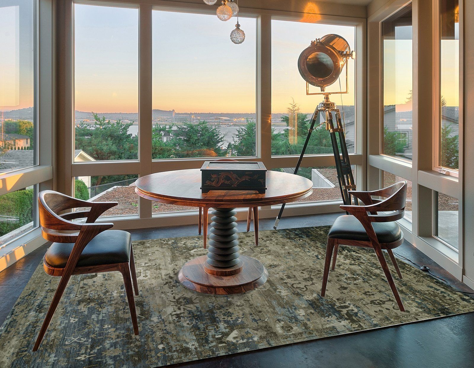 Stylish seating area with round table, two chairs, and city sunset view through large windows