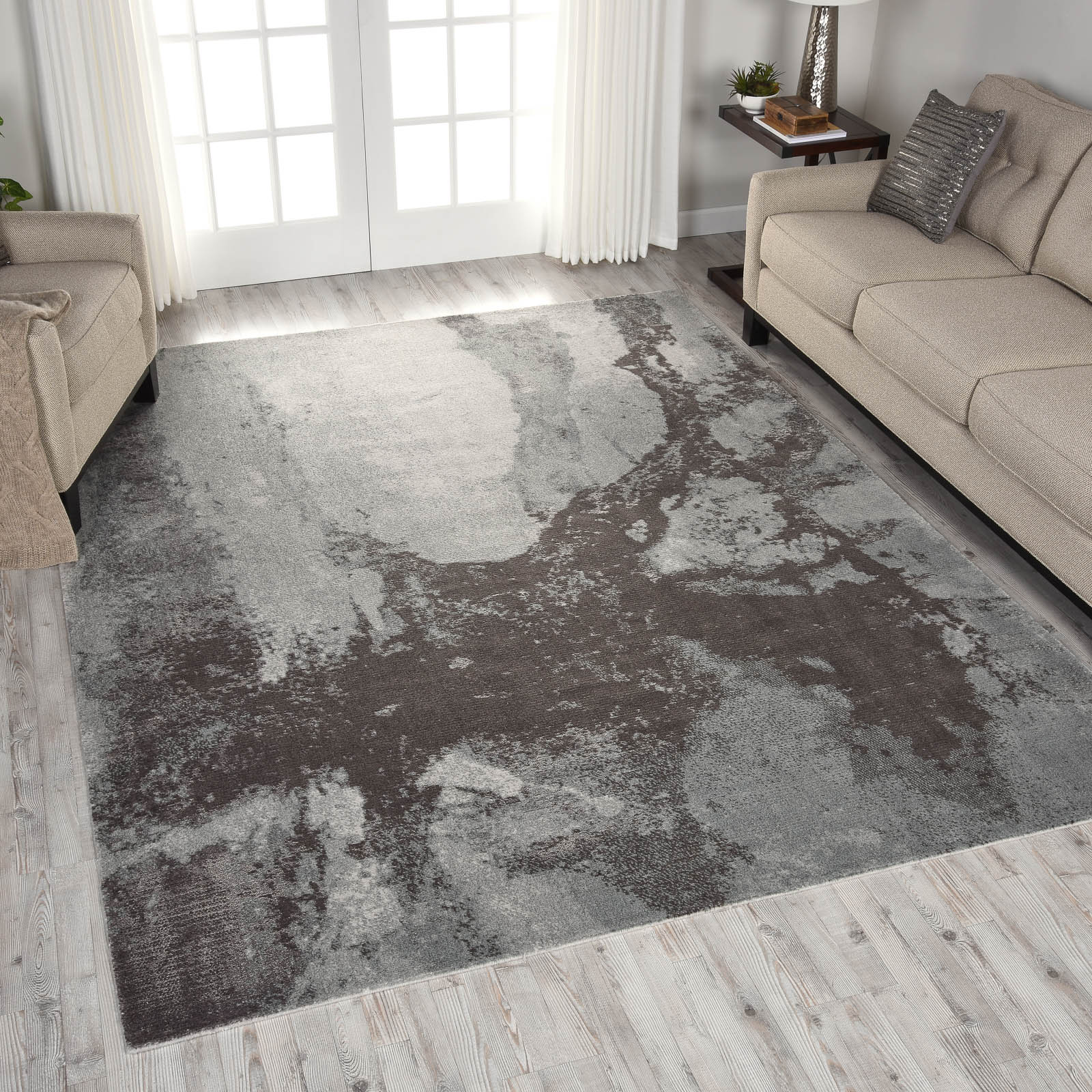 Living room with gray patterned area rug between beige sofas and a small side table