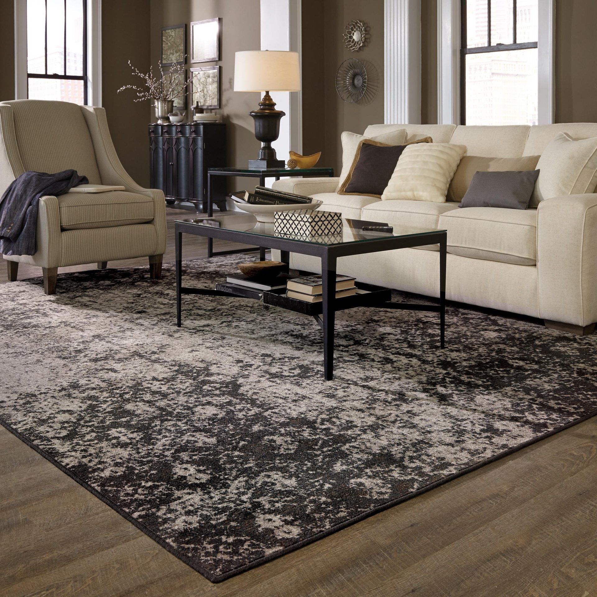 Modern living room with beige sofa, armchair, coffee table, and patterned rug on wood floor