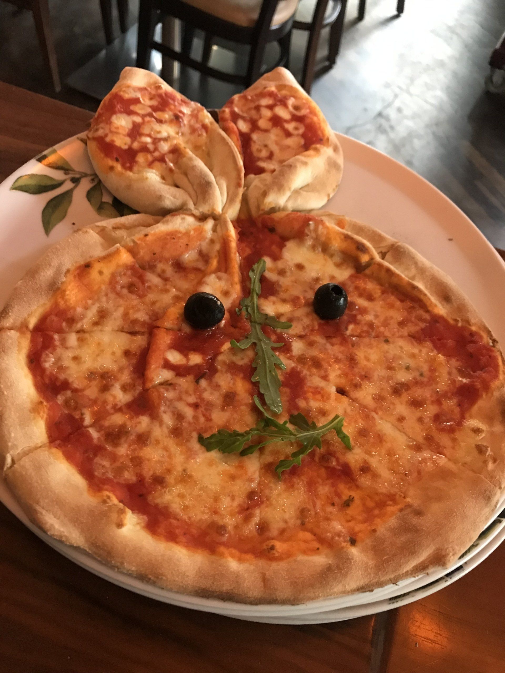 Eine Pizza, die wie ein Gesicht mit Oliven darauf aussieht