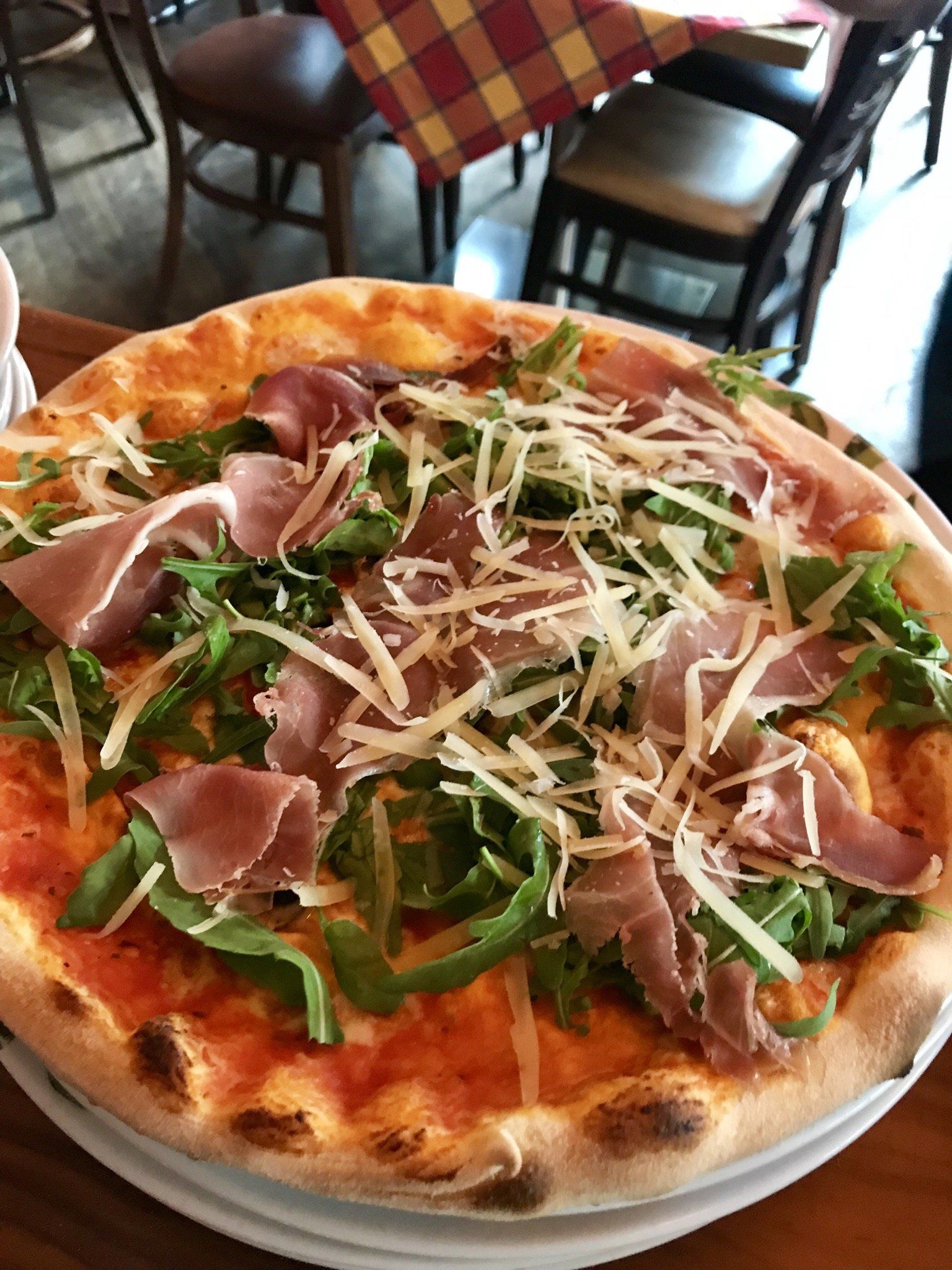 Eine Pizza mit Fleisch und Käse liegt auf einem Teller auf einem Tisch.