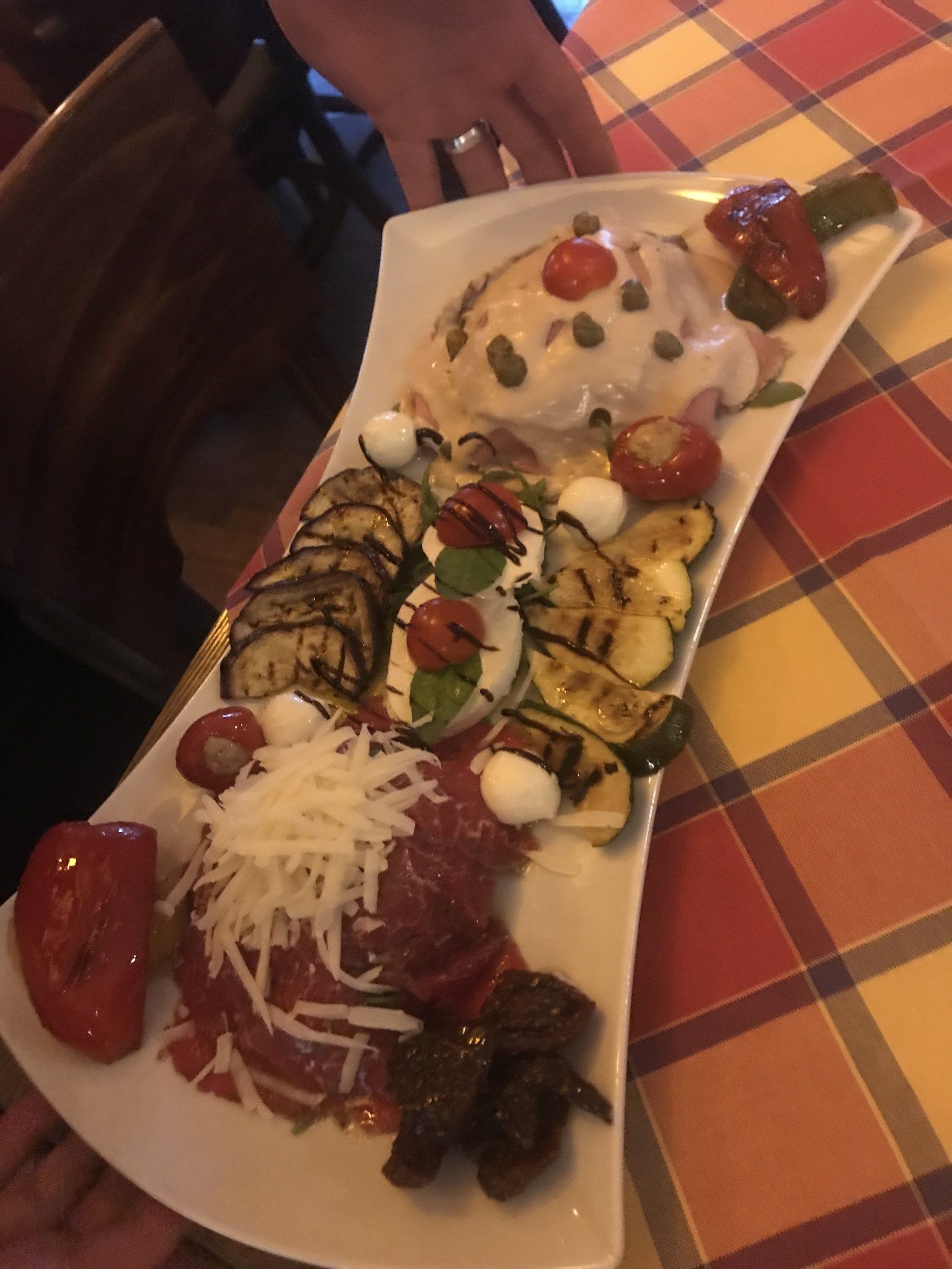 Eine Person hält einen Teller mit Essen auf einem Tisch