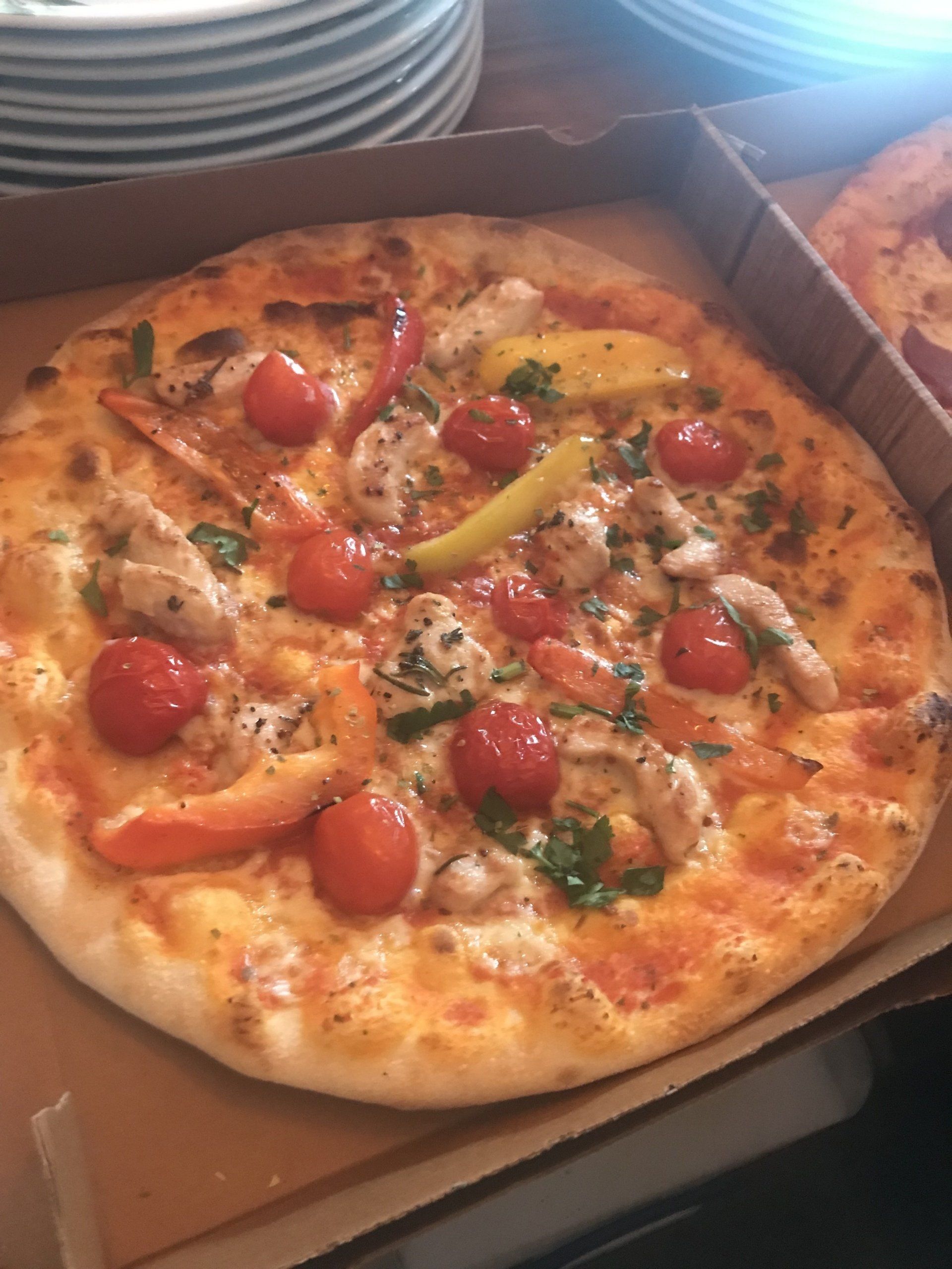 In einer Schachtel befindet sich eine Pizza mit Garnelen, Tomaten und Paprika.